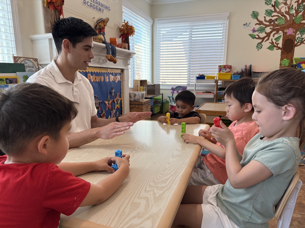 A teacher guiding a small group as they build and count with linking cubes