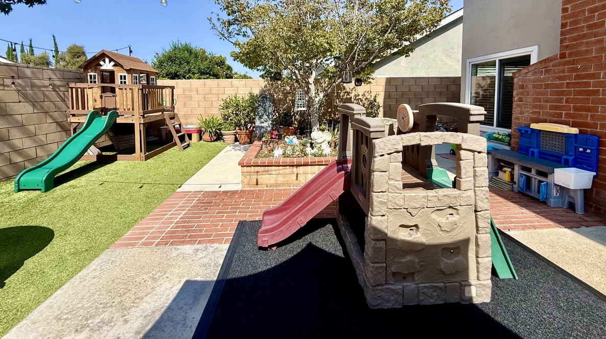 The play yard with climbing structures, slides, and a garden